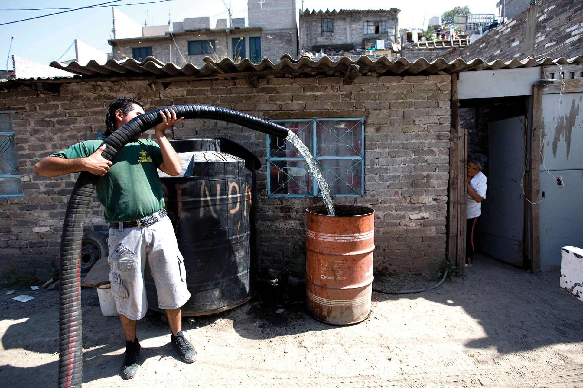 A city worker uses a hose from a truck to deliver a weekly water ration in a low-income Mexico City neighborhood. (Photo by Eduardo Verdugo/Associated Press.)