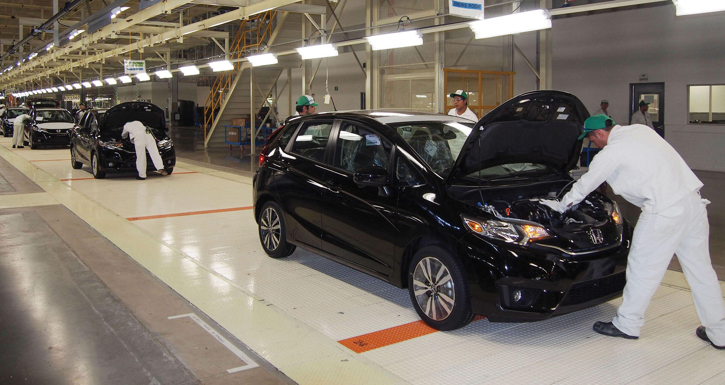 Workers inspect cars rolling off a modern brightly-lit assembly line at the new Honda plant in Celaya, Mexico. (Photo by Kydpl Kyodo/Associated Press.)