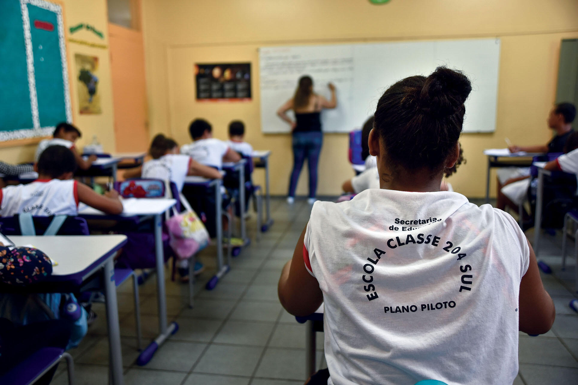 A young Afro-Brazilian woman sits in a class of students participate in a pilot program that supports nutrition, transportation, and extracurricular activities, July 2017. (Photo by Pillar Pedreira/Agência Senado.)